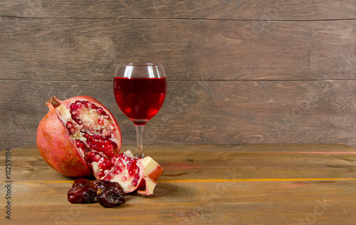 pomegranates, figs, and a glass of wine on a wooden surface
