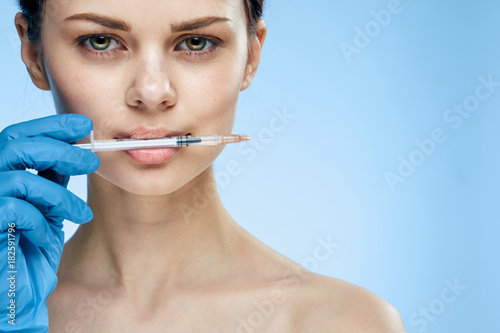 girl in a latex glove with a syringe on a blue background