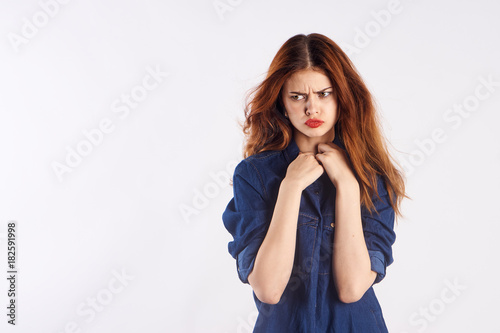 on a light background red-haired girl in a blue shirt, empty space for copy