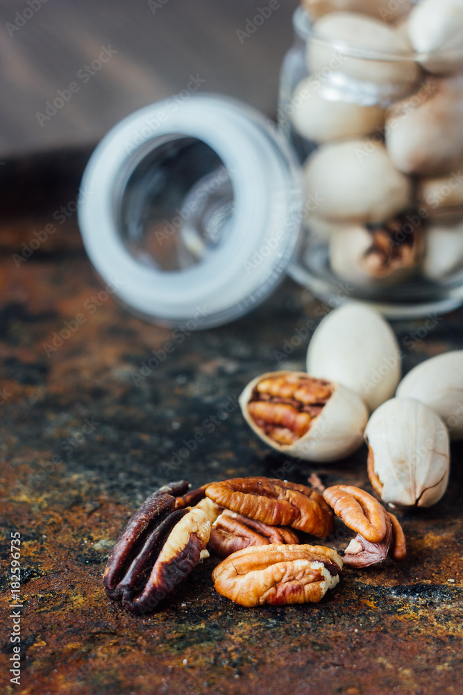Pecan nuts inside glass jar on rustic surface. Pecan nuts inside glass jar on rustic surface.