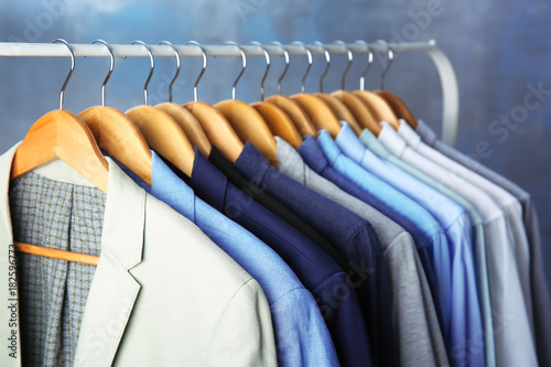 Male jackets and shirts hanging on clothing rail indoors