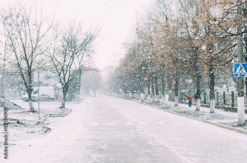 Snowfall on the street. The road is in the snow, in the air a lot of snowflakes are flying