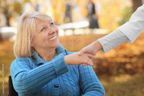 Senior woman and young caregiver outdoors