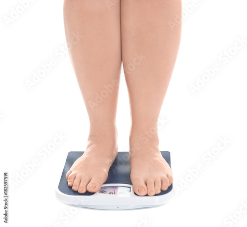 Overweight woman measuring her weight using scales on white background