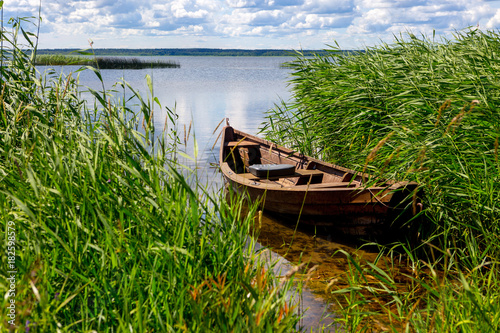 A boat near the shore. Blue sky  water  grass. The concept of fishing  recreation  travel.