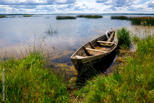 A boat near the shore. Blue sky  water  grass. The concept of fishing  recreation  travel.