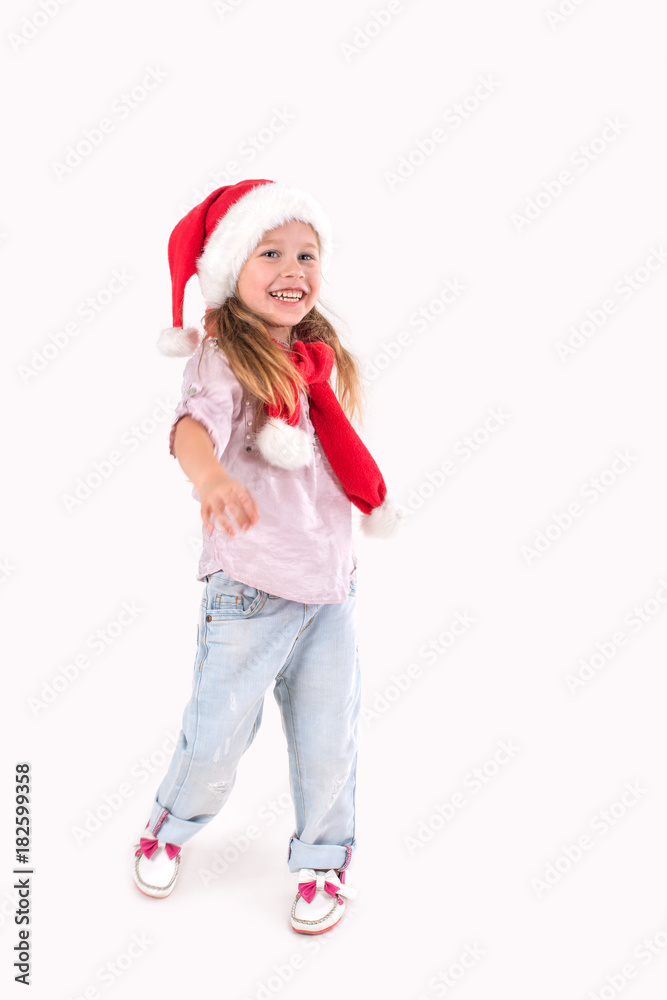 the girl in Santa Claus's cap stands and smiles.