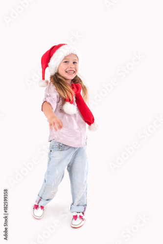 the girl in Santa Claus's cap stands and smiles.