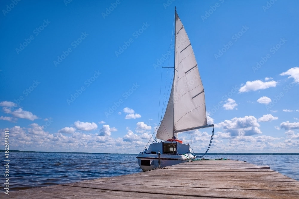 Naklejka premium The yacht is near the pier. Blue sky and water. The concept of recreation and travel.