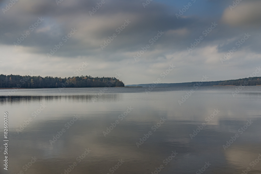 Fototapeta premium A calm blue lake with a wobbly cloud in the sky