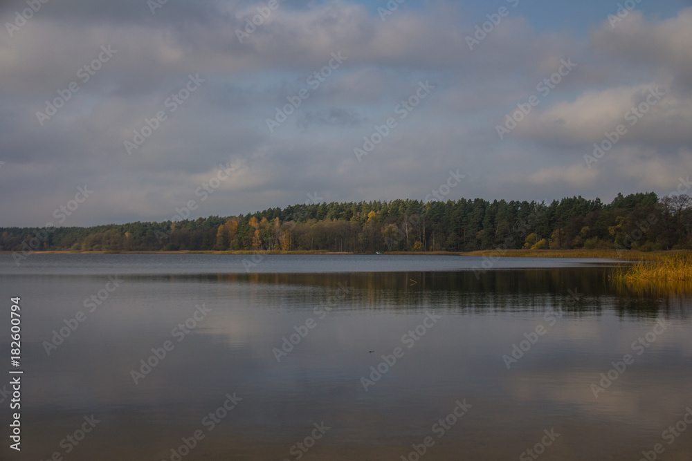 Tranquil lake with clouds in the sky and trees in autumn colors