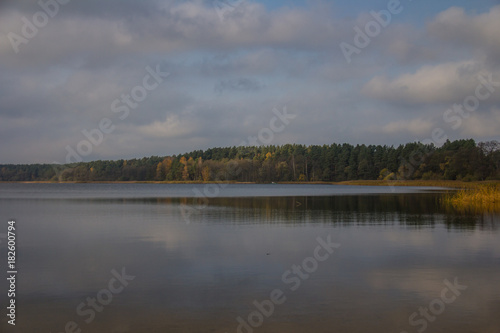 Tranquil lake with clouds in the sky and trees in autumn colors