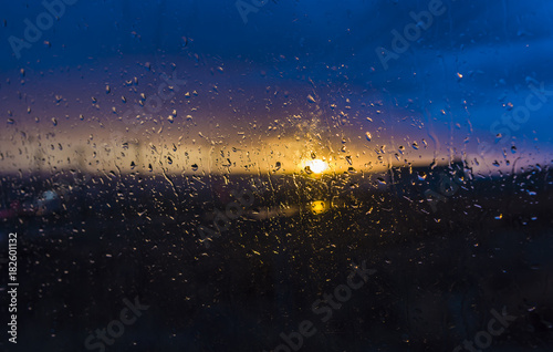 Water drops on a window glass after the rain. The sky with clouds and sun on background. drop on the glass window