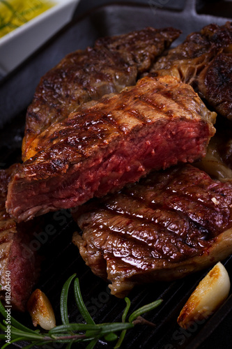 Grilled beef steak with spices close up on dark background