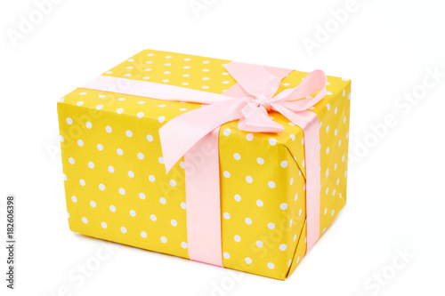Yellow dotted gift box. Big yellow gift box with a pink ribbon isolated on white background. Holiday and celebrations concept.