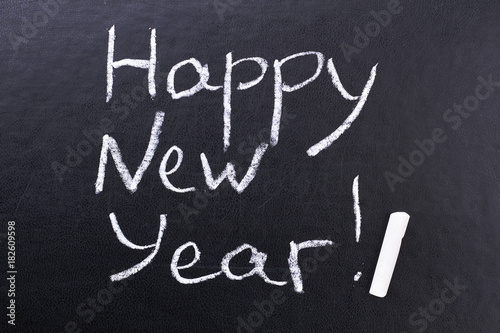 Inscription Happy New Year on black board. Black board with hand inscription Happy New Year with chalk.