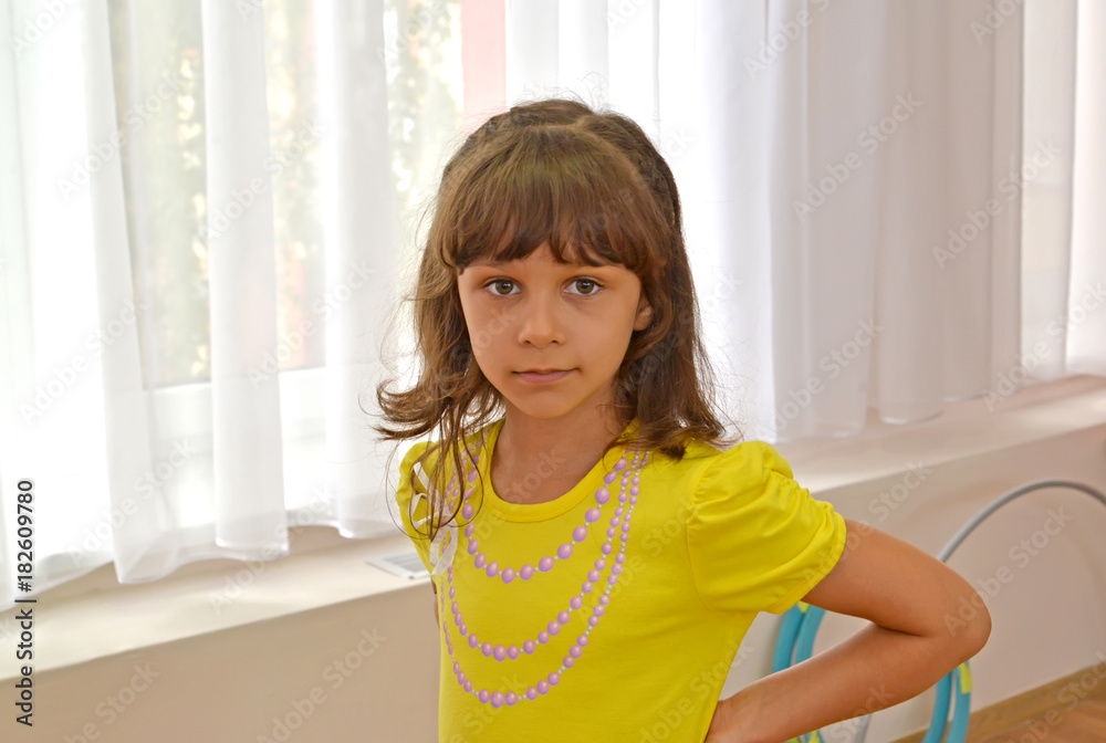 Portrait of the little girl against the background of a window in kindergarten