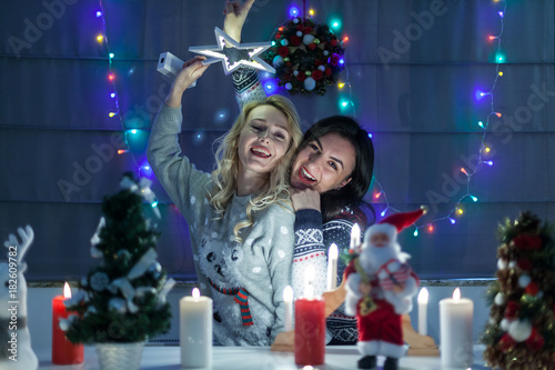 Happy female friends playing in christmas decorated interior and having fun. Merry Christmas and Happy New Year