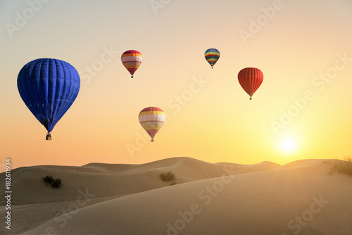 Air ballons flying over desert at sunset