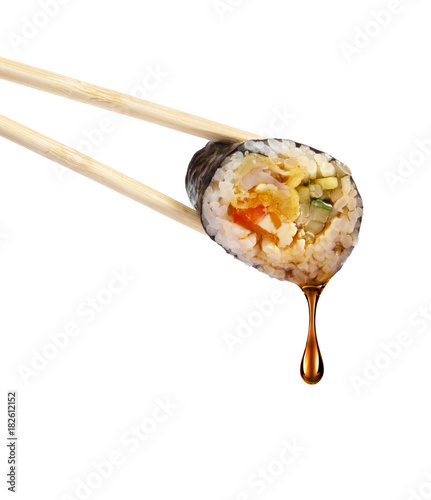 Drop of soy sauce drips from a sushi roll, isolated on white background