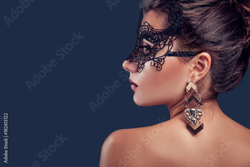 Beautiful brunette model wearing lace carnival mask and jewellery. New year party.