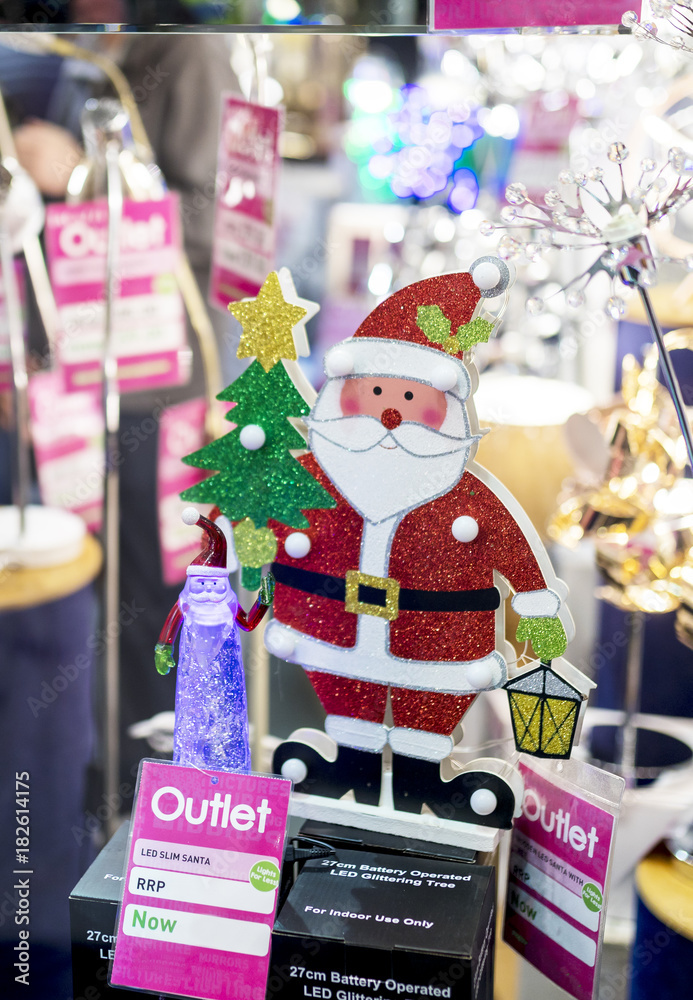 Jolly glitter Santa Claus figure holding a lantern in a lighting shop window to promote and celebrate Christmas