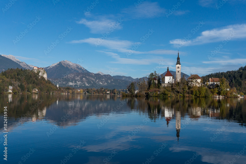 The famous lake bled island and church in the foreground with the castle and the alps in the backdrop