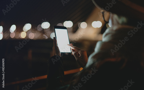 Cropped image of woman holding mobile phone with blank copy space screen for your text message or advertising content, female surfing the web on smartphone while relaxing outdoors.