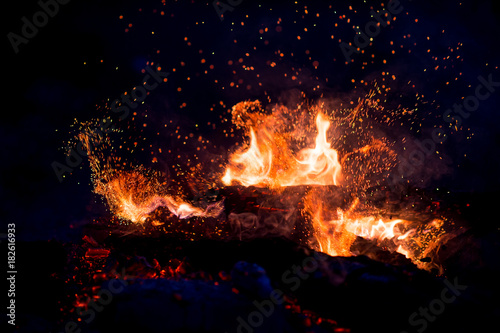 Burning woods with firesparks, flame and smoke. Strange weird odd elemental fiery figures on black background. Coal and ash. Abstract shapes at night. Bonfire outdoor on nature. Strenght of element.