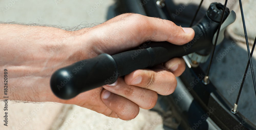 Panorama of side view of Man pumping bicycle tyre outdoors, close-up of hands