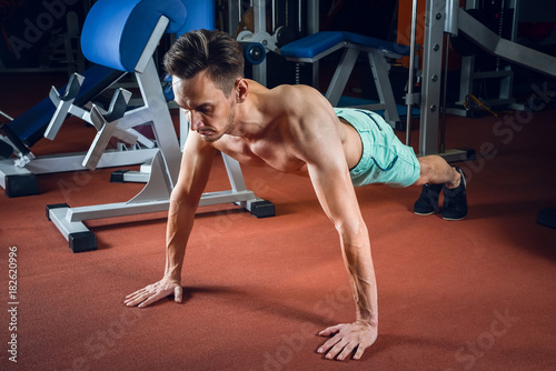 Handsome caucasian man working out and doing push ups at gym. Bodybuilding  sport and fitness lifestyle.