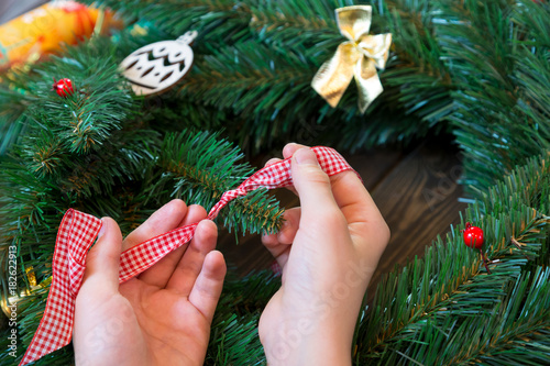 kid's hands hold red and white ribbon for decoration of the christmas wreath. new year concept