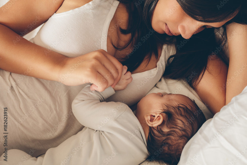 Young woman with a sleeping baby in bed Young woman with a sleeping baby in bed