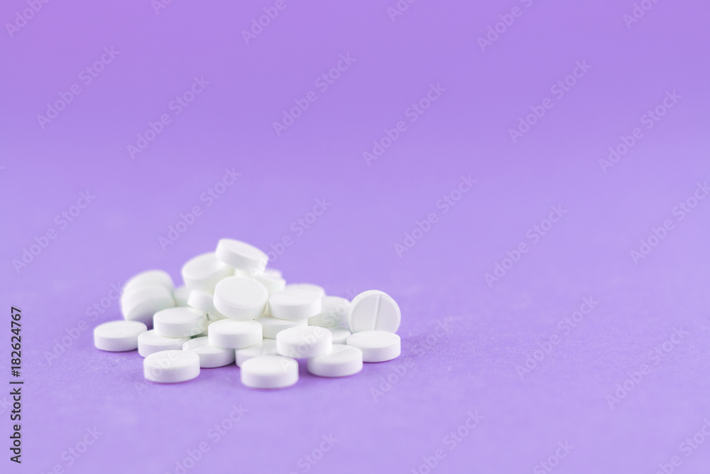 Close up white pills on purple background with copy space. Focus on foreground, soft bokeh. Pharmacy drugstore concept