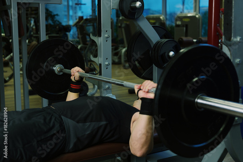 Close-up of a man holding his hands with a barbell for pulling, squatting, fitness in the gym. Concept sports, toned picture, copyspace for text