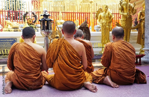 Monks sitting and praying in front of temple in Thailand