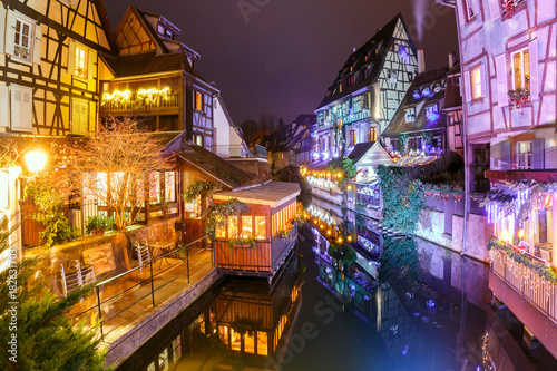 Traditional Alsatian half-timbered houses in Petite Venise or little Venice, old town of Colmar, decorated and illuminated at snowy christmas night, Alsace, France