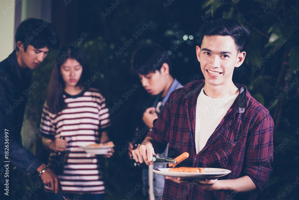 Asian group of friends having outdoor garden barbecue laughing with alcoholic beer drinks on night Asian group of friends having outdoor garden barbecue laughing with alcoholic beer drinks on night