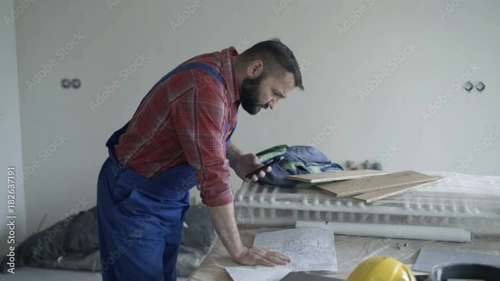 Young man working with smartphone and blueprints at new home
Young man working with smartphone and blueprints at new home