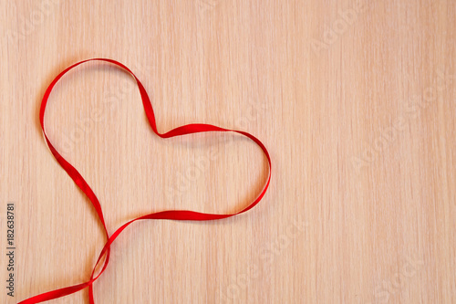 Red Ribbon Heart on a wooden background. Valentines Day concept