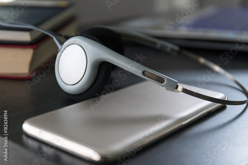 Headphones with book and mobile phone on wood table