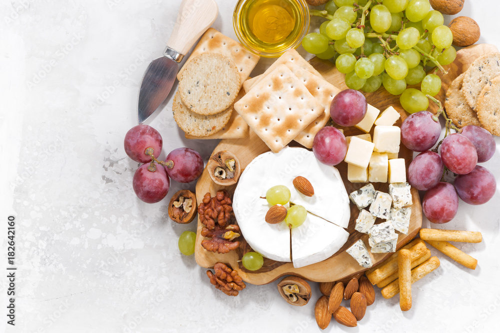 camembert, grapes and snacks on a white table, top view camembert, grapes and snacks on a white table, top view