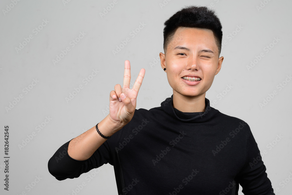 Portrait of Asian young tomboy making peace sign Portrait of Asian young tomboy making peace sign