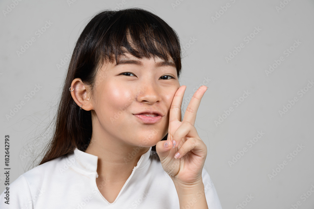 Portrait of beautiful young Asian woman against white background