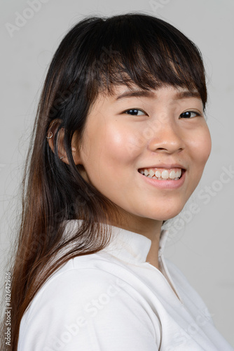 Portrait of beautiful young Asian woman against white background