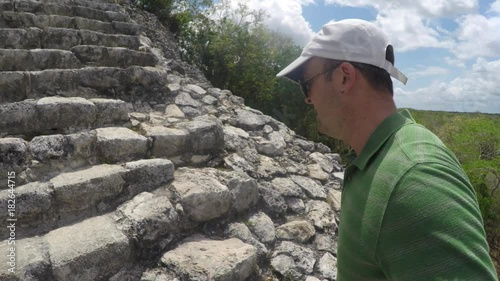 Man climbs big stairs at Ek Balam Mayan ruins in Mexico photo