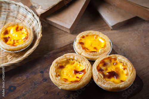 Delicious Egg tart, traditional Portuguese dessert, on wooden plate for coffee break on rustic wooden table.