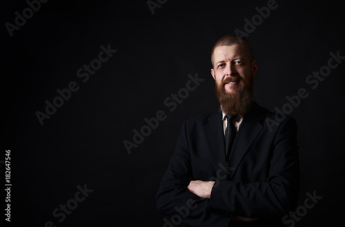 businessman with beard posing in black shirt on dark background in studio. place for copy-paste