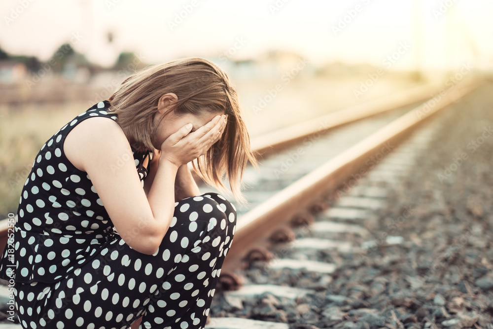 Sad woman with depression sitting on railway track