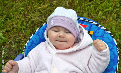 Little child in a hat on a background of green grass.